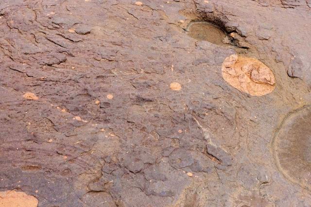 [Matsieng Footprints] Bílé kruhy na hnědé skále, vpravo nahoře údajně Měsíc v úplňku, vlevo od něj planety